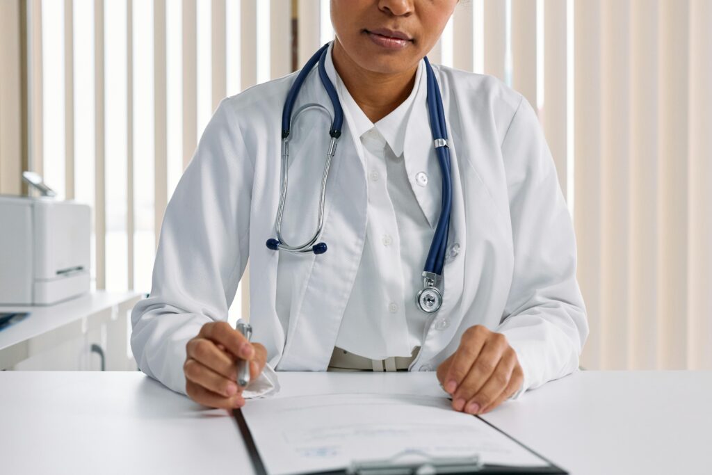 A focused doctor with stethoscope recording patient details in an office setting.
